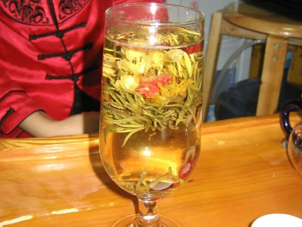 Im Glas öffnet sich die "Kunsttee"-Kugel und heraus wächst eine Blüte