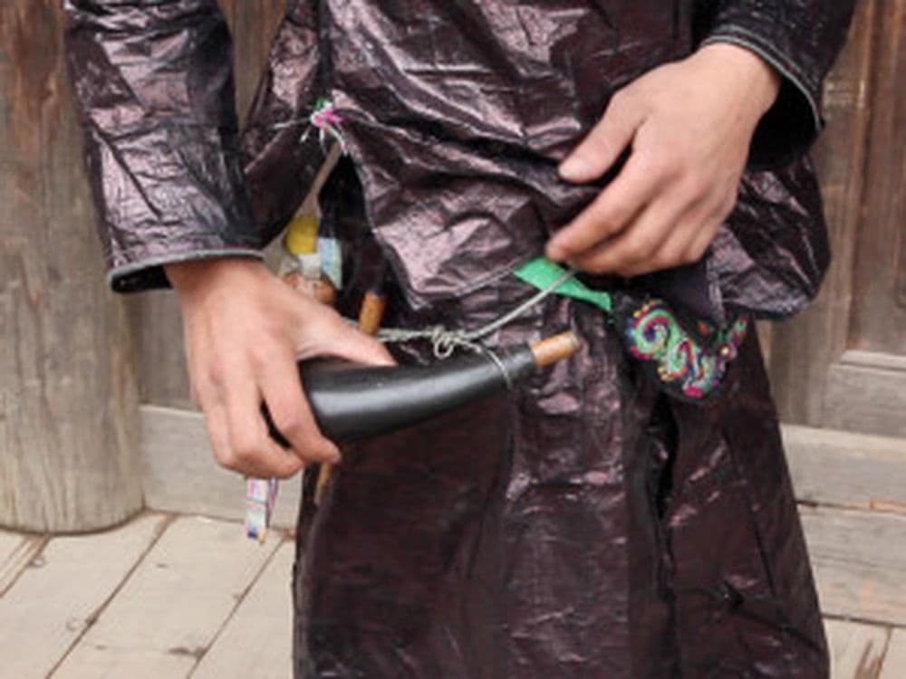 Gun Shuige trägt das traditionelle Pulverhorn