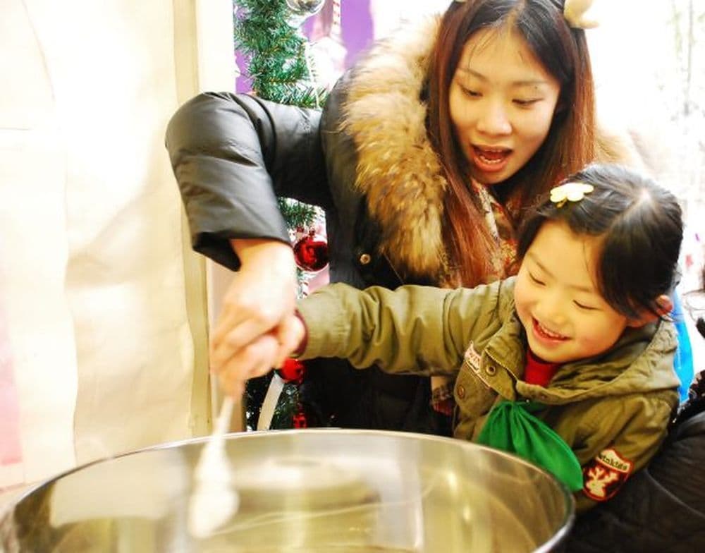 Chinesisches Kind bekommt Zuckerwatte auf Weihnachtsmarkt in Shanghai.