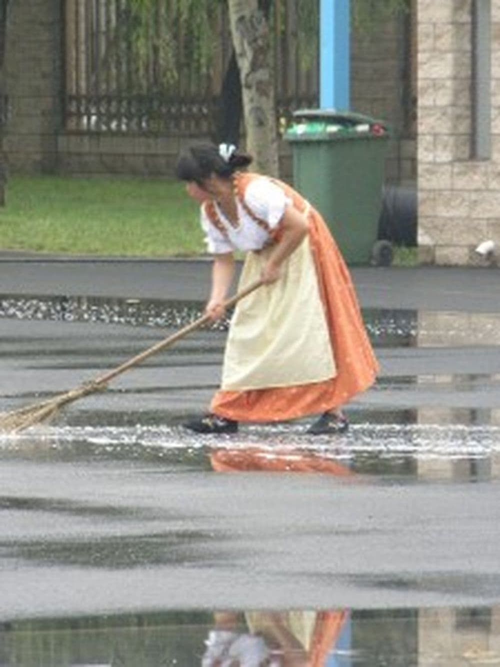 Eine Chinesin im bayerischen Dirndl fegt auf dem riesigen Gelände.